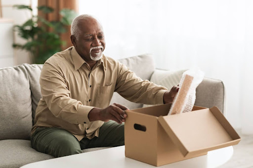 senior man unpacking box in living room