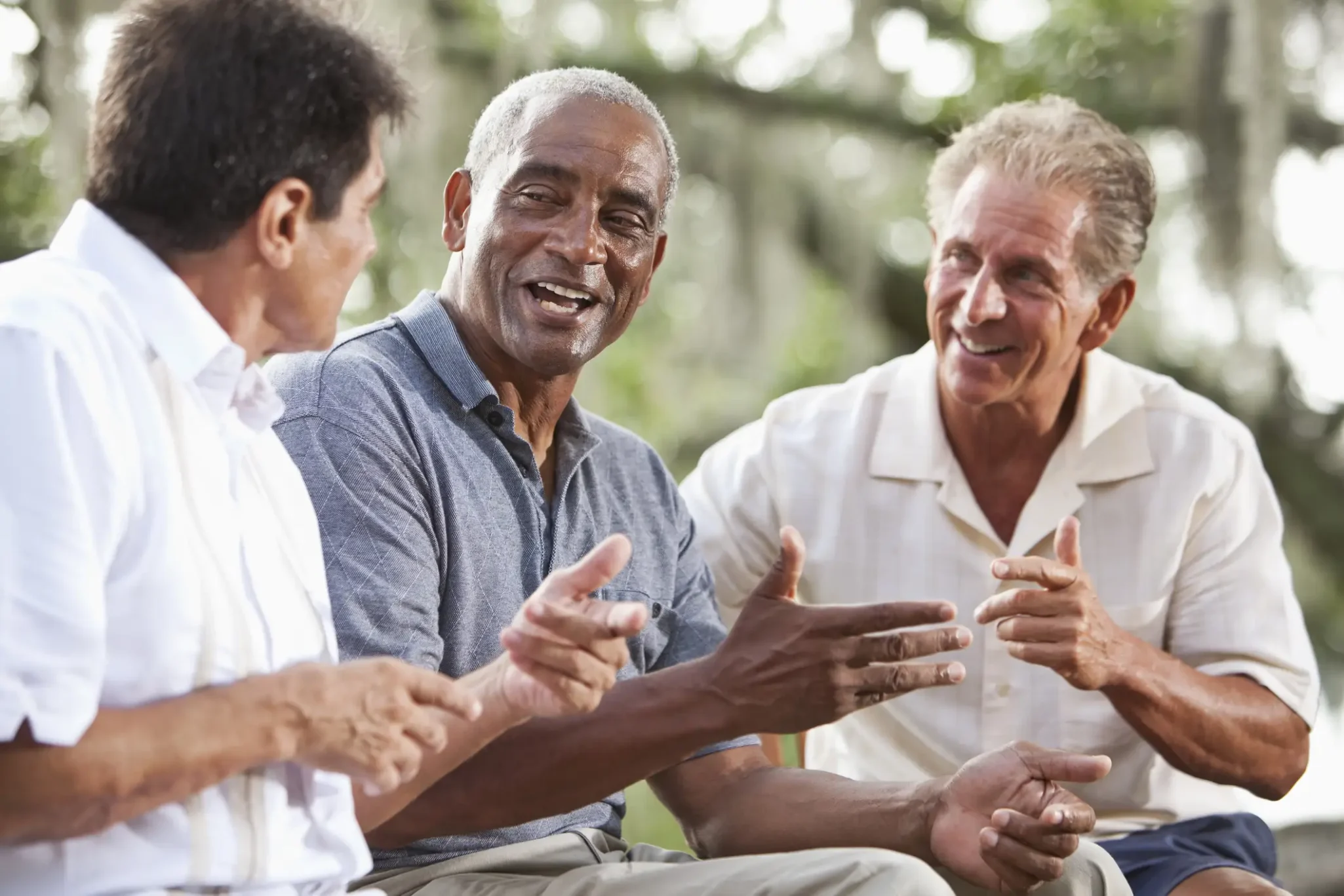 Three senior men smiling and chatting outdoors