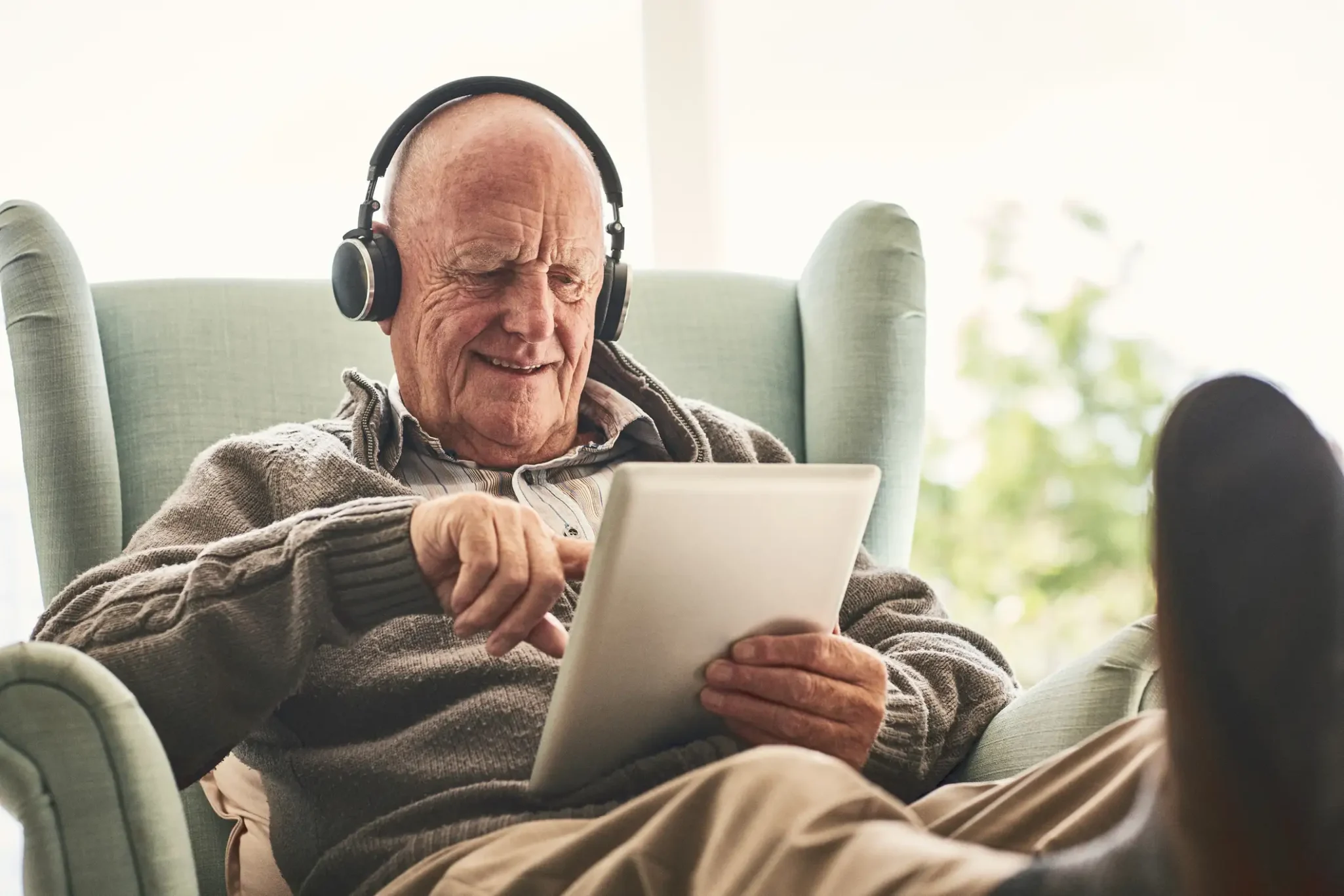 Senior man wearing headphones while using an app on a tablet