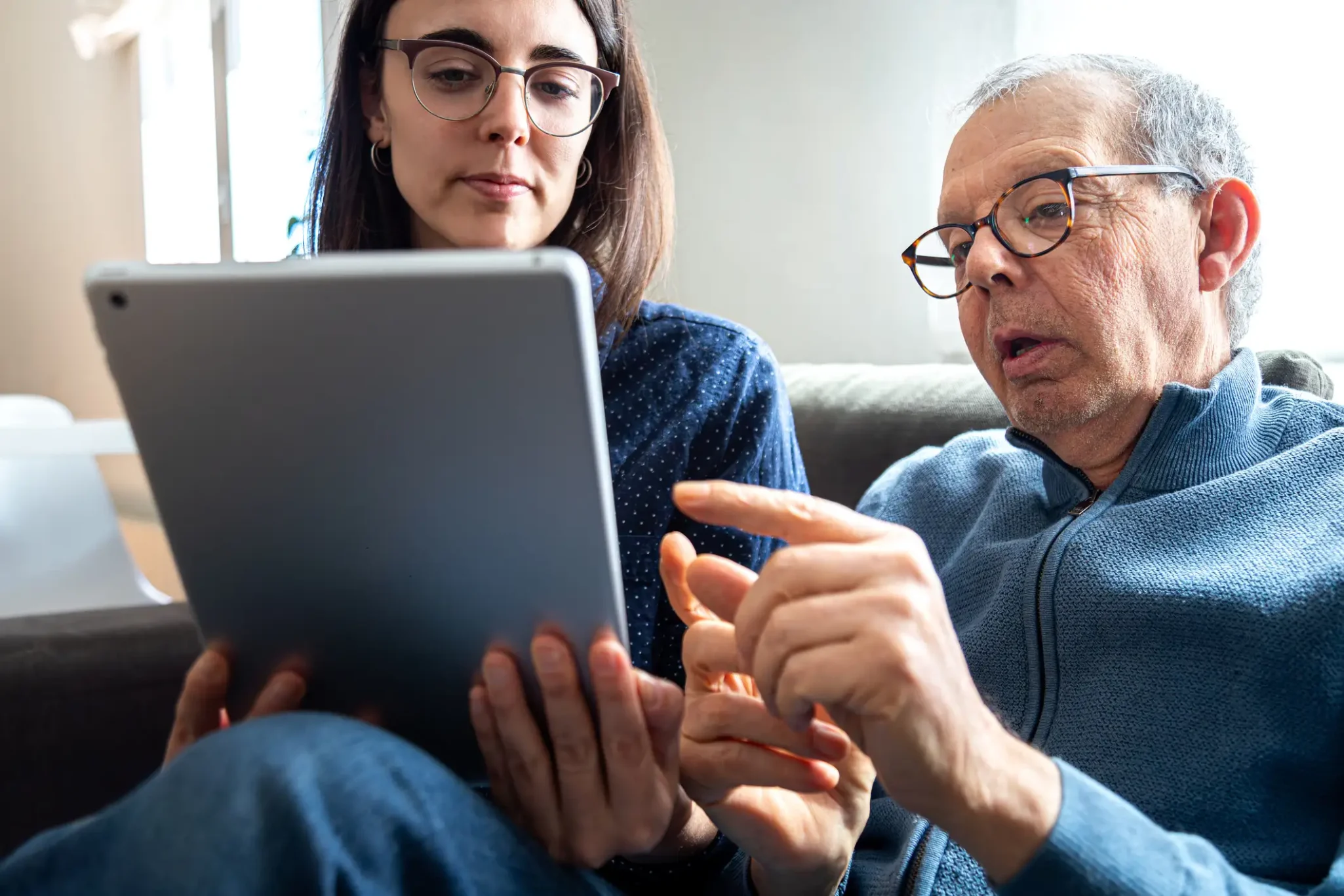 Senior man and his adult daughter using an app on a tablet
