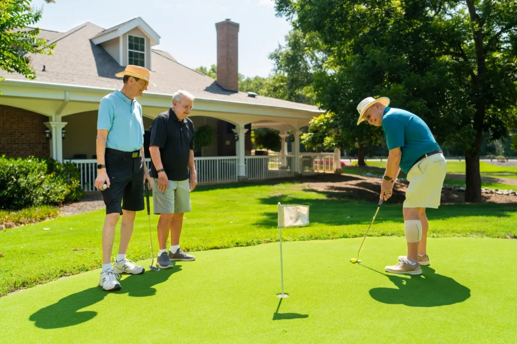 3 residents of Brandon Wilde on putting green, among senior favorite's senior living amenities in Evan, GA, is the golf course.
