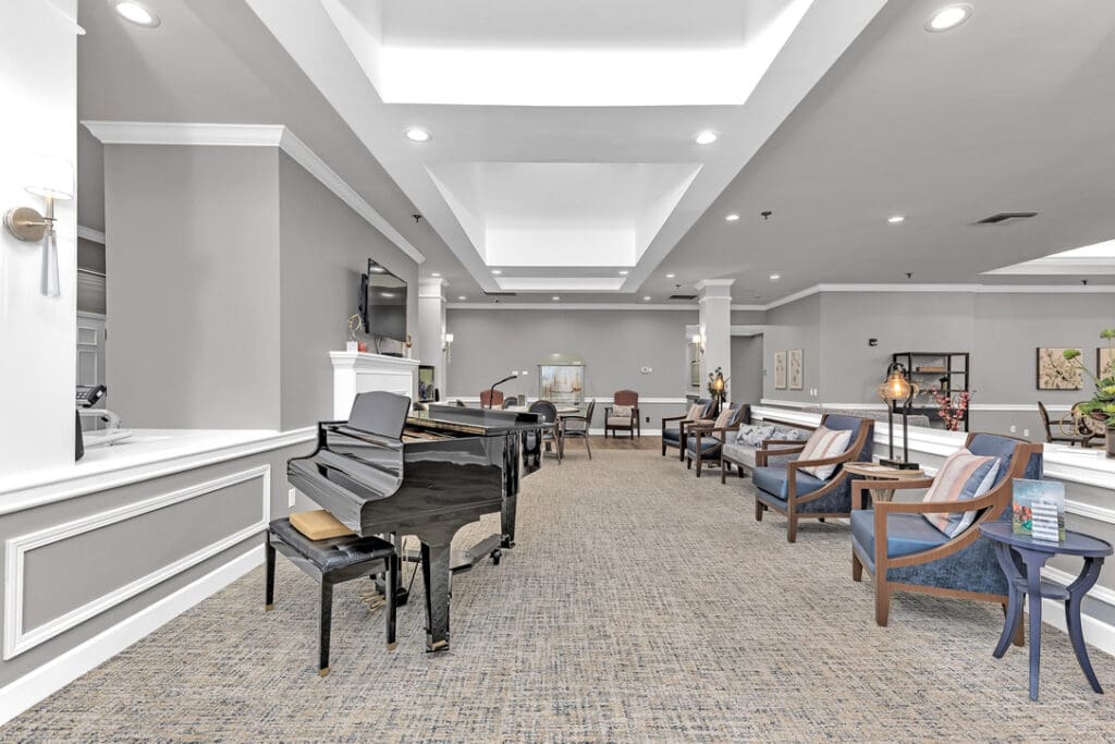 A recreation room in The Colonnade with chairs and a piano