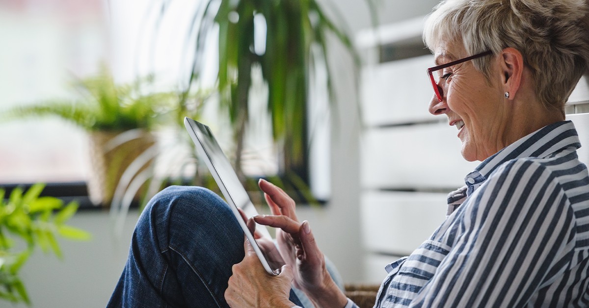 senior searching the internet on a tablet while sitting down outside