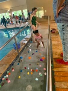 a small child gathering Easter eggs by the pool