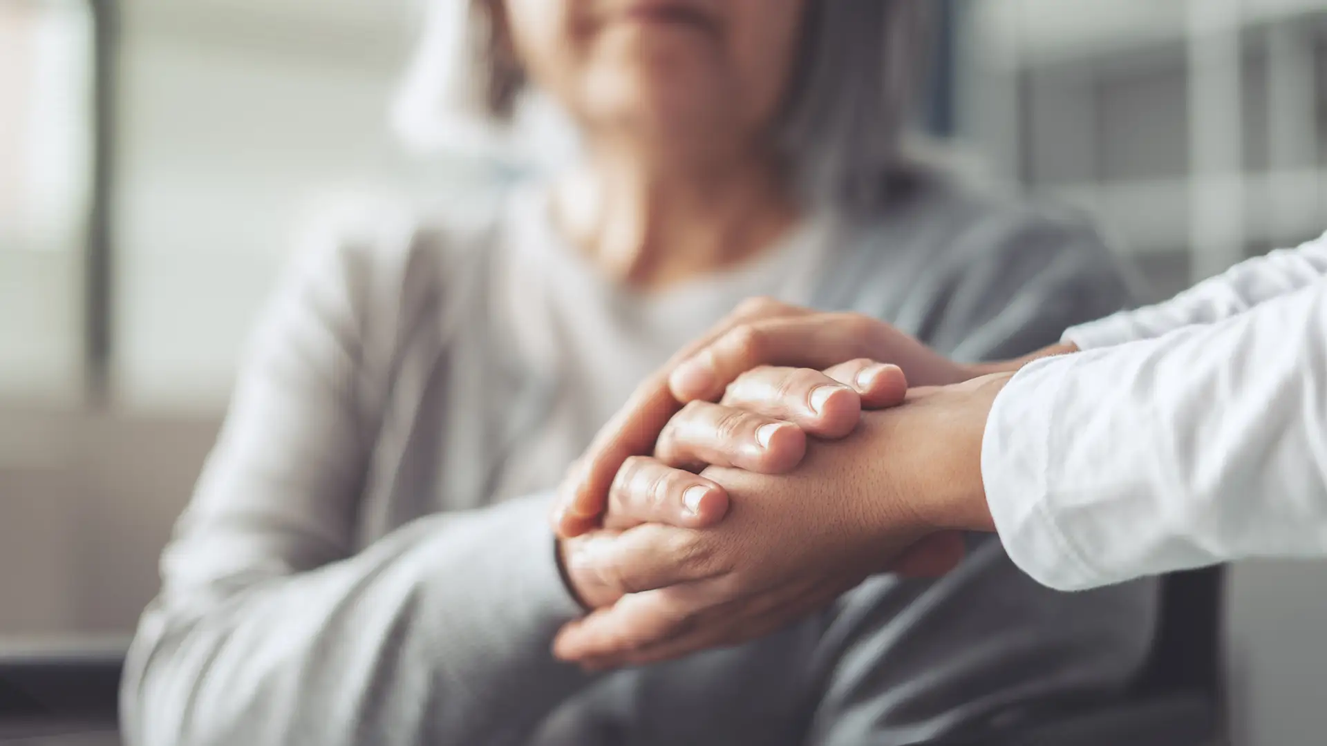 Close-up of a senior woman holding hands with her caregiver